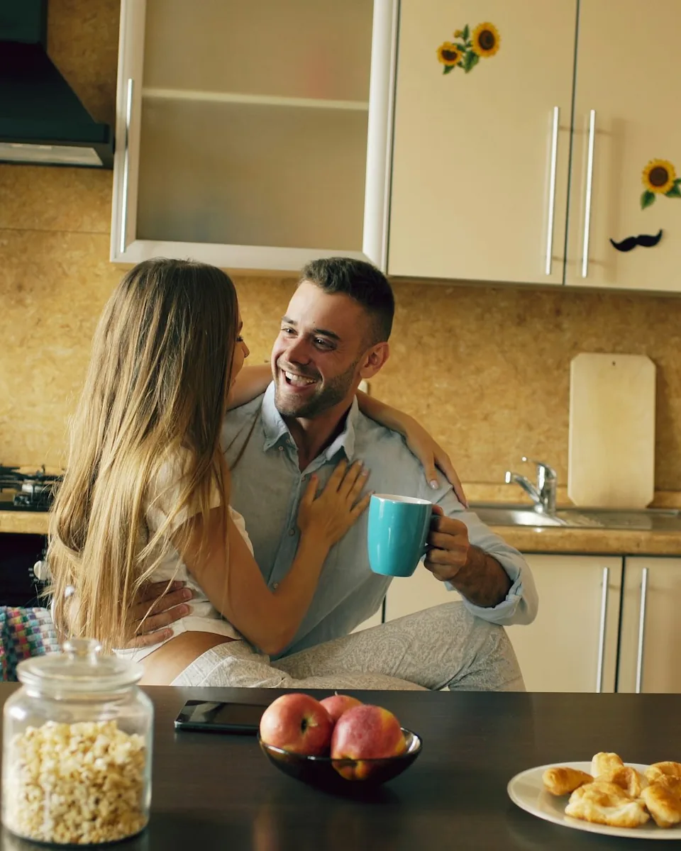 A couple laughing over coffee at their kitchen table