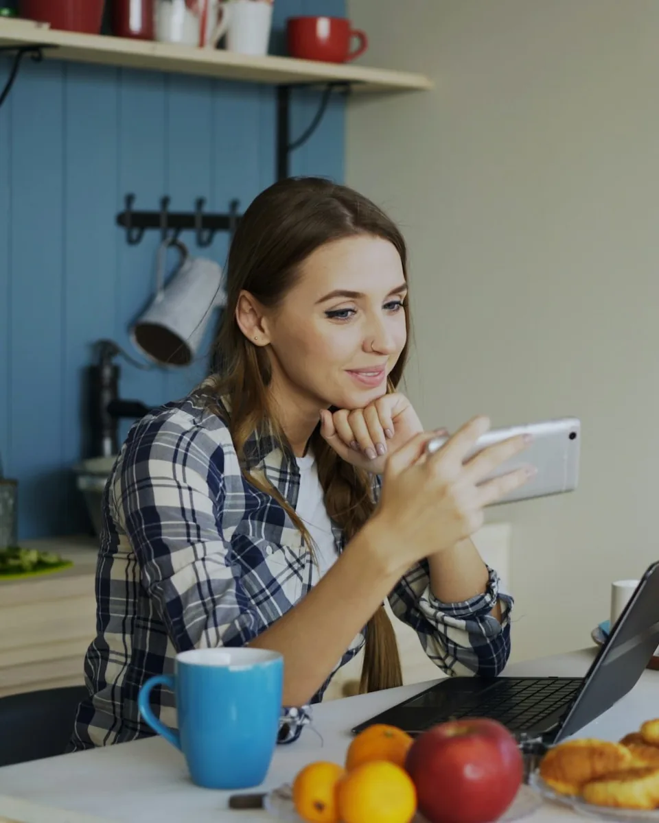 A woman at her kitchen table with coffee, looking at her phone