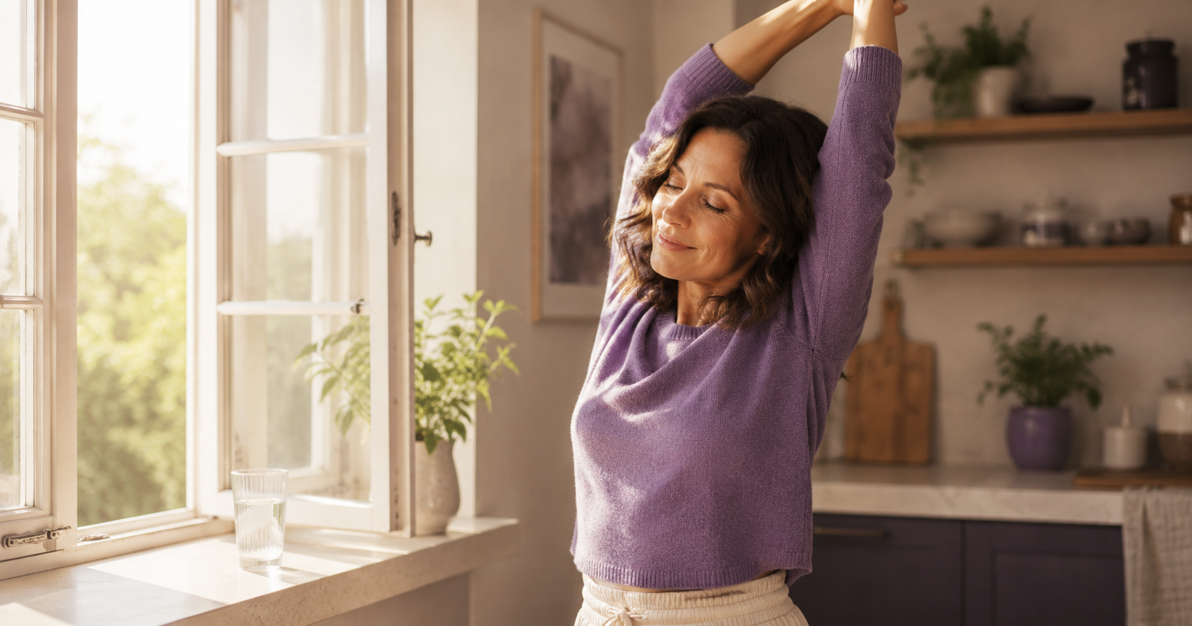 A woman standing and stretching by an open window with a glass of water on the sill, mid-morning light.